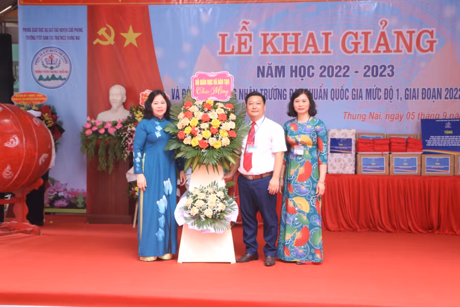 Thứ trưởng Bộ GD&amp;ĐT Ngô Thị Minh (bìa trái) tặng hoa chúc mừng nhà trường.