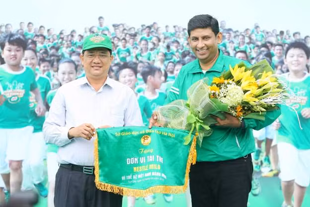 Ông Phạm Xuân Tiến – Phó Giám đốc Sở GD&ĐT Hà Nội trao hoa, cờ lưu niệm cho ông Ganesan Ampalavanar - Tổng giám đốc Công ty Nestlé Việt Nam