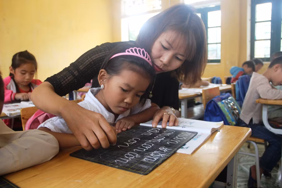Cô giáo nắn nót từng nét chữ cho học trò. Ảnh: Hồng Đức