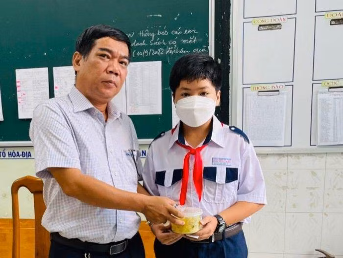 Thầy Lâm Ngọc Thành, Phó Hiệu trưởng Trường THCS Nguyễn Trãi (TP Long Xuyên, tỉnh An Giang) trao phần ăn sáng cho học sinh tại trường