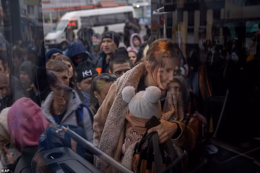 Một phụ nữ bế con khi cô lên xe buýt rời Kyiv, Ukraine, hôm thứ Năm. Giao thông tắc nghẽn trên các tuyến đường chính của thủ đô bất chấp lời kêu gọi người dân ở nhà (ảnh AP)