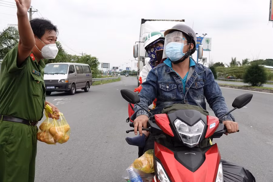 Chiến sĩ công an tham gia hỗ trợ phát quà và giúp đỡ chỉ dẫn người dân trên tuyến đường quốc lộ 1A (ảnh Duy Tân).
