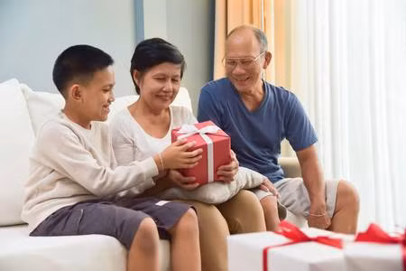 89273395-happy-asian-family-a-boy-giving-a-red-gift-box-to-his-grandfather-and-grandmother-for-birthday-chris.jpg