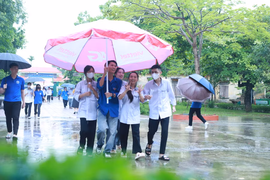 Các thí sinh được thanh niên tình nguyện hỗ trợ che mưa bằng ô cỡ lớn từ cổng vào sân trường. Ảnh: Đình Tuệ. Các thí sinh được thanh niên tình nguyện hỗ trợ che mưa bằng ô cỡ lớn từ cổng vào sân trường. Ảnh: Đình Tuệ.