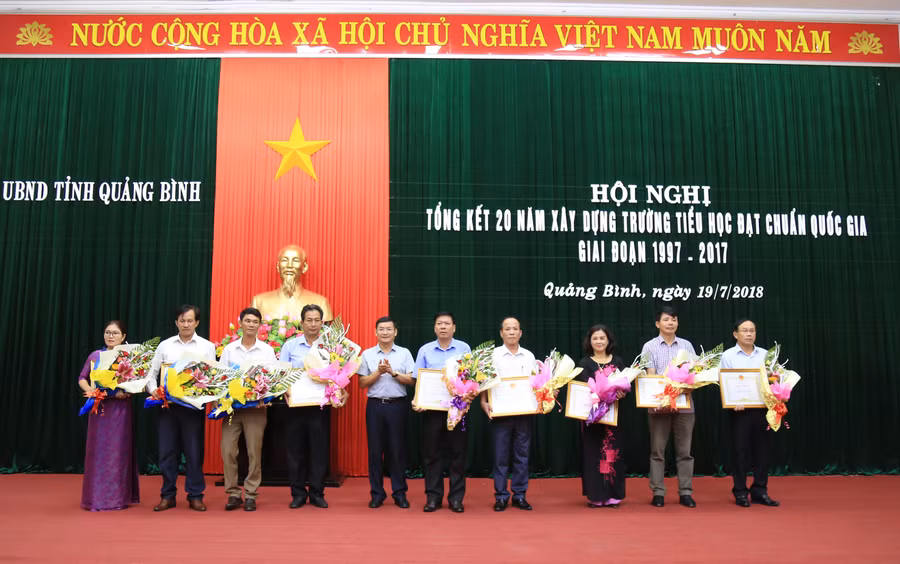 Ông Trần Tiến Dũng trao bằng khen của chủ tịch UBND tỉnh Quảng Bình cho những đơn vị xuất sắc trong phong trào xây dựng trường Tiểu học chuẩn Quốc gia trong 20 năm qua.