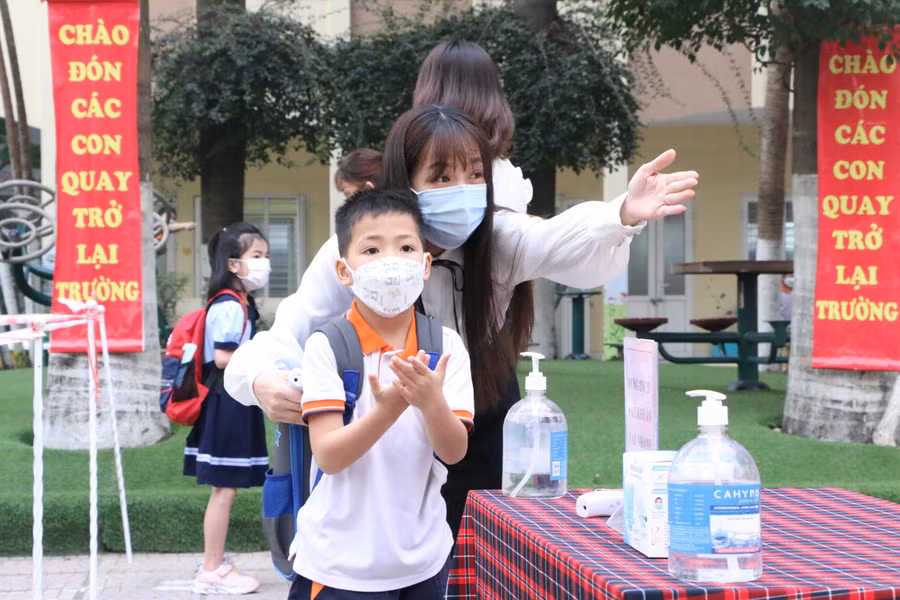 Học sinh thực hiện sát khuẩn tay và đeo khẩu trang khi tới lớp để phòng dịch Covid-19. 