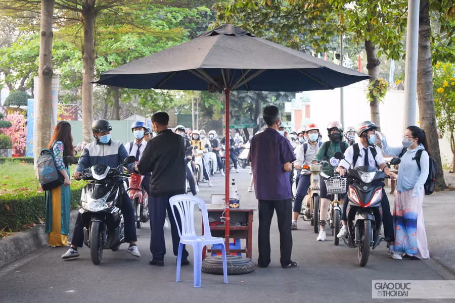 Học sinh xếp thành hàng dài, không chen lấn và giữ khoảng cách an toàn để chờ thầy cô đo thân nhiện.