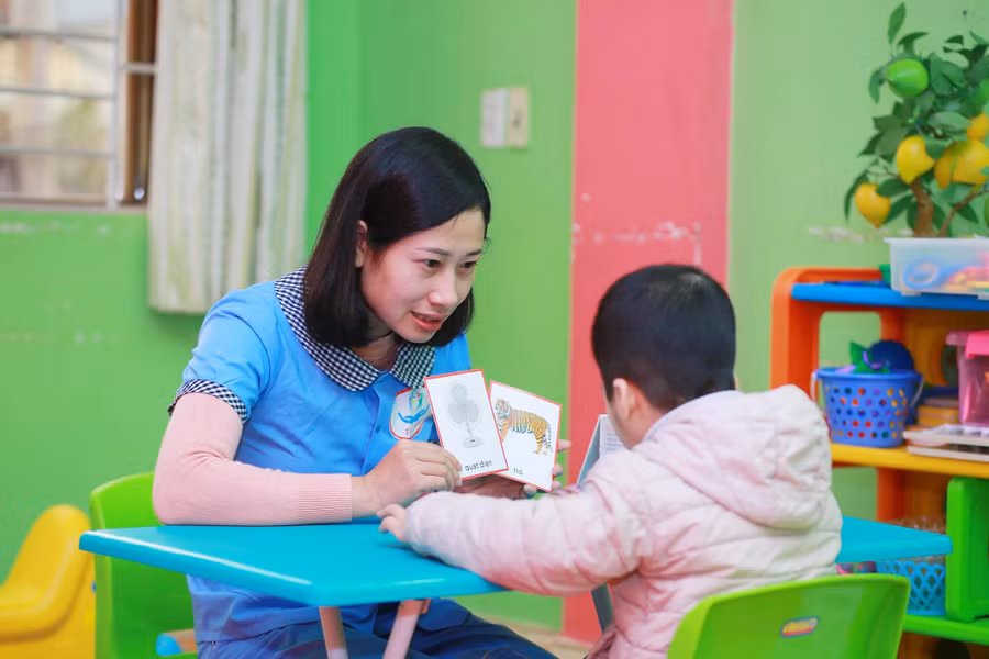 Giáo viên chuyên biệt đang dùng phương pháp can thiệp để dạy trẻ tự kỷ
