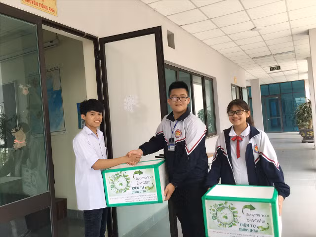 Thịnh và Vân (mặc áo khoác đồng phục) mang thùng rác điện tử đến tặng cho các lớp 