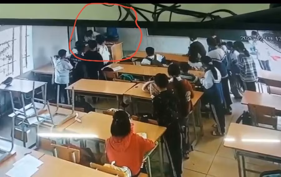 Vị phụ huynh côn đồ (áo xanh) đang tấn công học sinh mặc đồng phục được camera ghi lại