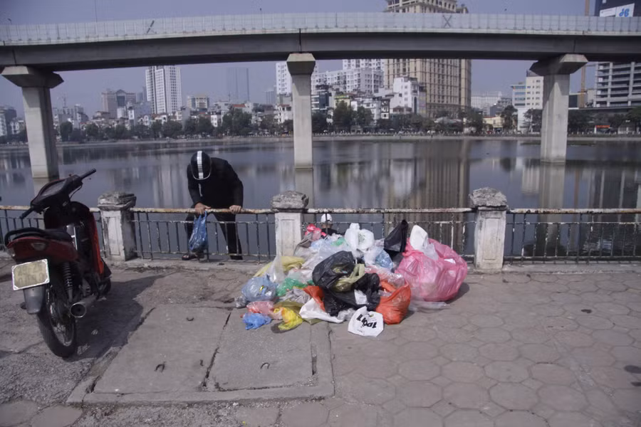 Trên vỉa hè cạnh hồ, túi nilon được chất thành đống gây mất mỹ quan