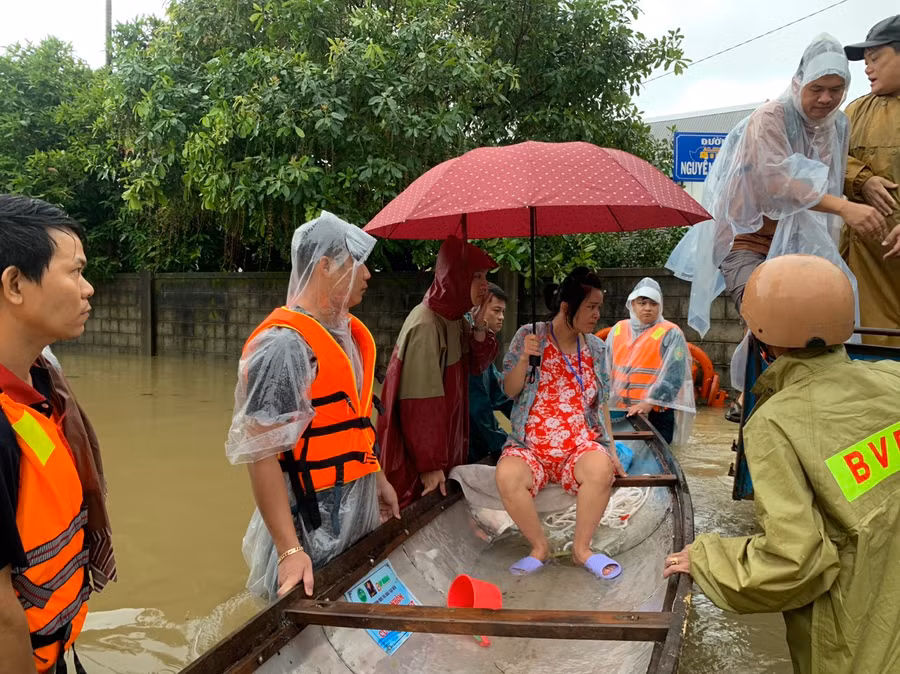 Công an đưa thai phụ lên ghe vượt lũ đến bệnh viện sinh. (Ảnh: CACC)