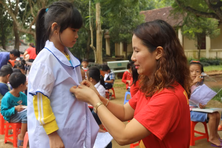 Cô giáo Dương Thị Thu Hà, Hiệu trưởng Trường tiểu học Hoàng Hoa Thám tặng áo đồng phục cho học sinh vùng lũ