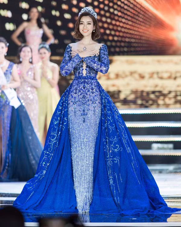 Hoa hậu Đỗ Mỹ Linh nổi bật trên sân khấu với thiết kế váy đính kết công phu của Lê Thanh Hòa. Từng chi tiết hoa nổi, tua rua đều được thực hiện thủ công để mang đến đường nét sắc xảo cho trang phục. Ngoài ra nhà thiết kế còn tạo khối ấn tượng cho phần tà váy.