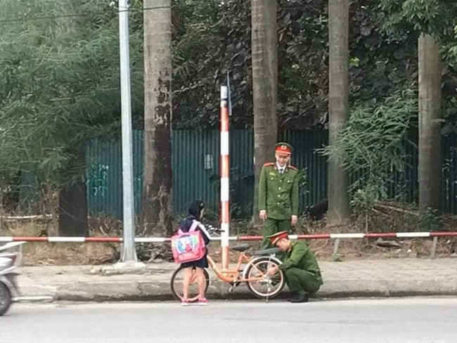 Hai chú công an vui vẻ giúp đỡ bé gái bị hỏng xe. 