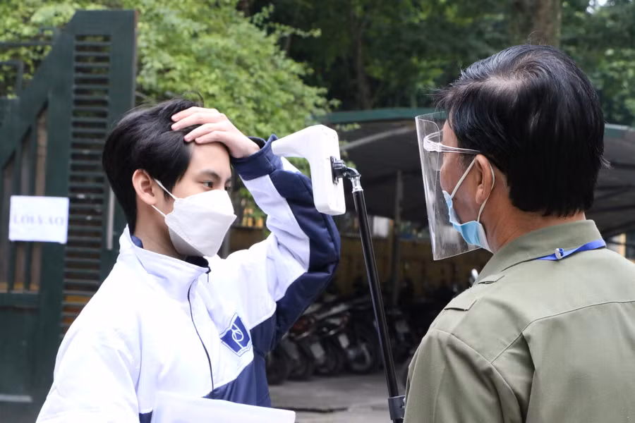 Học sinh khi đến được nhân viên đo thân nhiệt, yêu cầu sát khuẩn tay và đi vào khu vực khám sàng lọc.