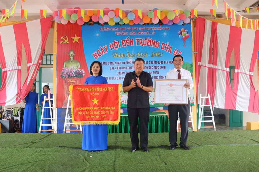 Cô Nguyễn Kim Anh (bìa trái) thay mặt nhà trường đón nhận "Cờ đơn vị dẫn đầu phong trào thi đua năm học 2021-2022" của UBND tỉnh Nam Định từ lãnh đạo huyện Hải Hậu trong lễ khai giảng năm học mới 2022-2023.