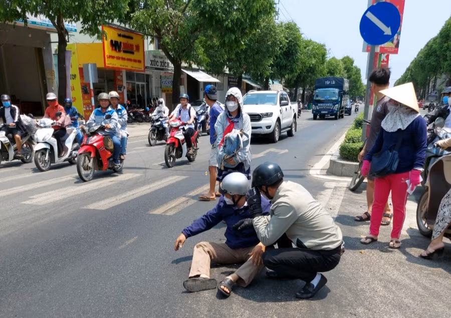 Phụ huynh đón con đi học về bị té ngã do vệt dầu nhớt đổ trên đường.