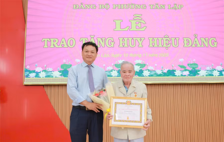 Ông Vũ Văn Hưng trao Huy hiệu 65 năm tuổi Đảng cho đảng viên Hà Học Tuấn. (Ảnh: Thành Tâm)
