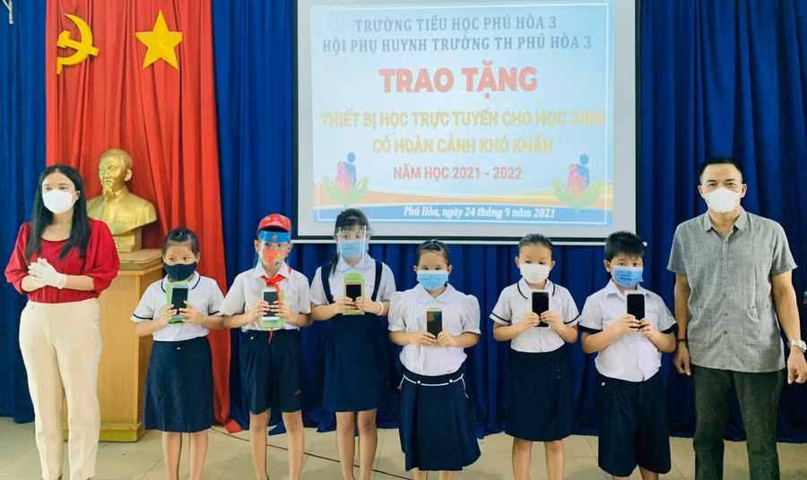 Ban Giám hiệu Trường TH Phú Hòa 3- TP. Thủ Dầu Một cùng nhà hảo tâm trao tặng thiết bị học tập cho HS có hoàn cảnh khó khăn trong mùa dịch (Ảnh: NTCC)