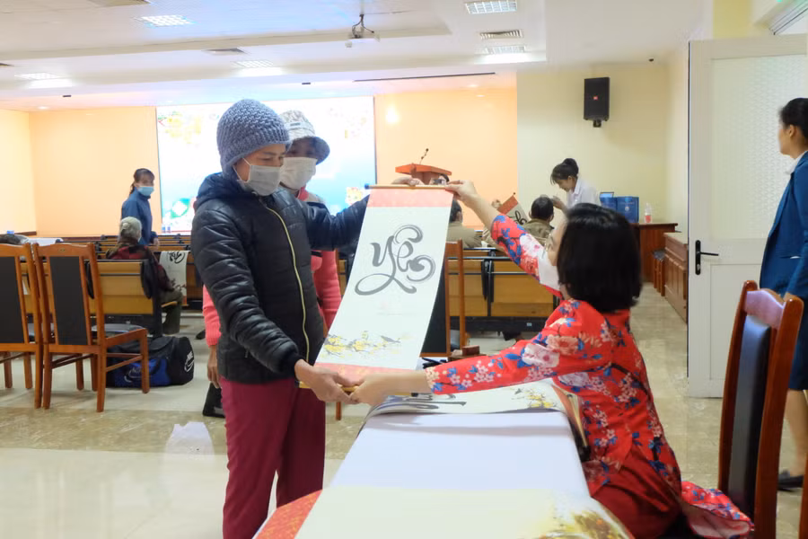 Bà Thử được tặng bức thư pháp có chữ Yên trước khi lên xe về quê. Ảnh: Hoàng Vinh.