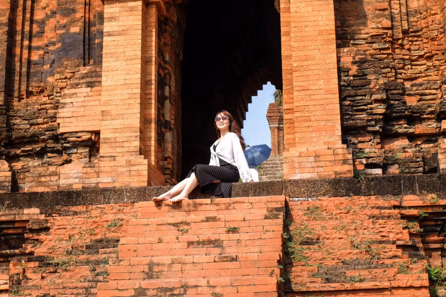 Diềm mái tháp hơi nhô ra nâng toàn bộ ba tầng mái, trang trí đơn giản nhưng khỏe khoắn. Phần móng tháp và thân tháp cách nhau một lớp đá ong. Họa tiết trang trí phần chân đế là những cột trụ kép tạc hình cánh hoa kép cách điệu đối xứng qua thân. Ảnh: Hoàng Vinh.
