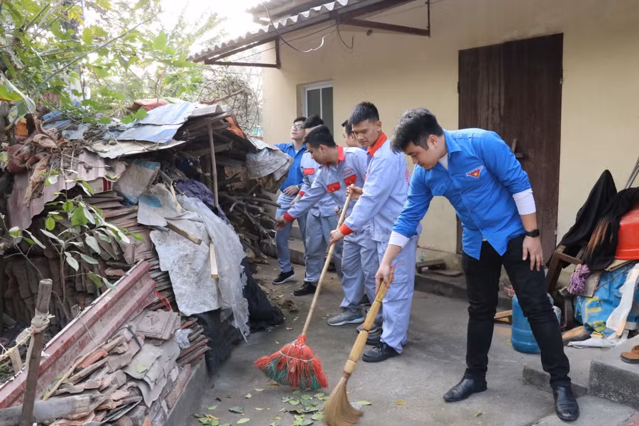 Sinh viên nhà trường quét dọn sân vườn nhà mẹ Việt Nam anh hùng Nguyễn Thị Sâu