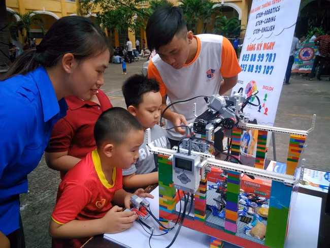 Các em học sinh hào hứng trải nghiệm các hoạt động khoa học và trò chơi robot gắp đồ vật.