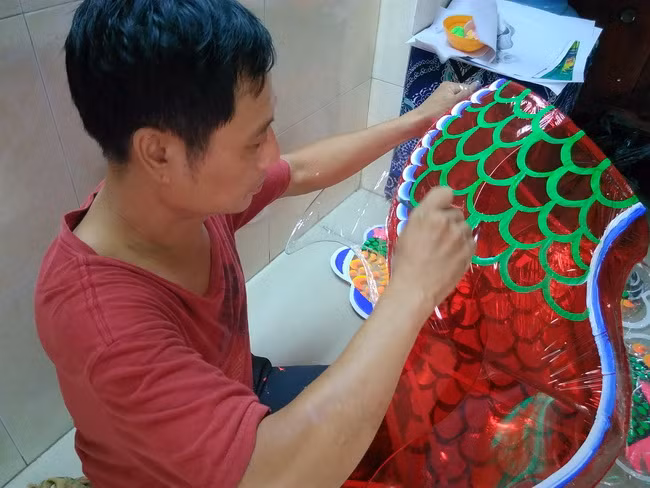 Anh Nguyễn Trọng Thành đang vẽ màu trang trí phần thân cho chiếc lồng đèn con rồng. Anh Nguyễn Trọng Thành đang vẽ màu trang trí phần thân cho chiếc lồng đèn con rồng.