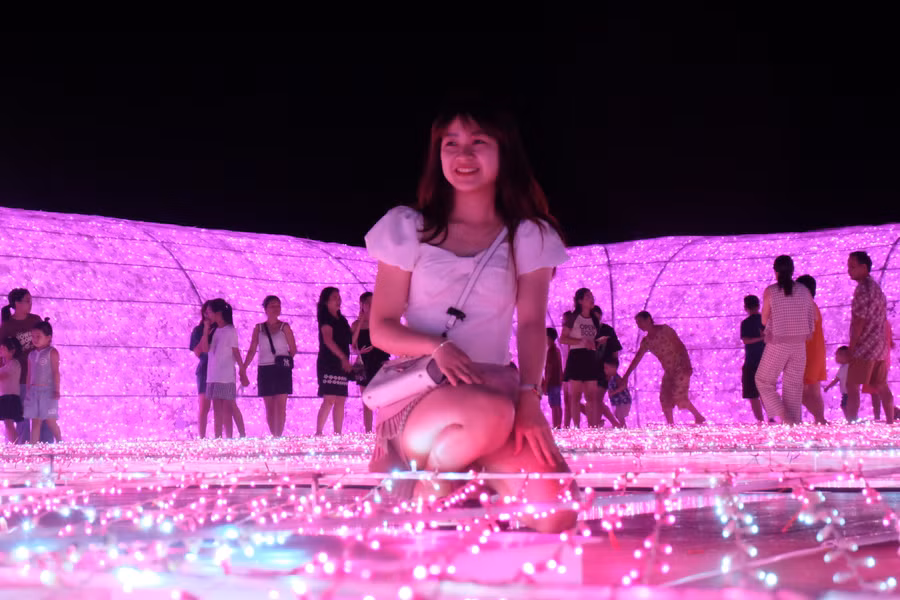 Người dân và du khách check in tại không gian ánh sáng nghệ thuật bên bờ tây cầu Rồng. Ảnh: Hoàng Vinh.