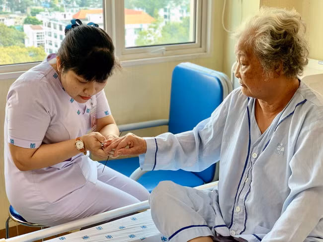Điều dưỡng đang chăm sóc móng tay cho bệnh nhân.