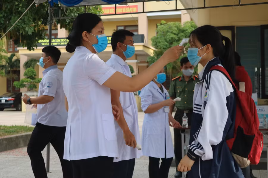 Thí sinh được đo, kiểm tra thân nhiệt trước khi vào trường thi.