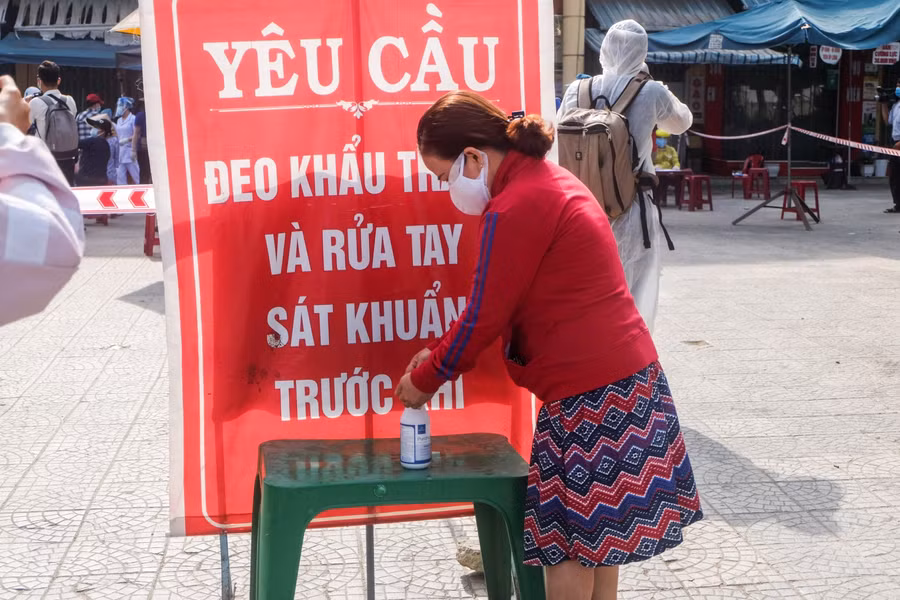 Người dân và tiểu thương rửa tay sát khuẩn trước khi vào khu vực đợi lấy mẫu xét nghiệm COVID-19.