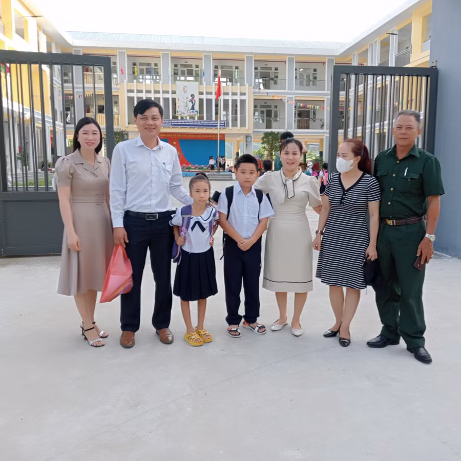 Đại diện chính quyền xã Hòa Bắc đứng đón các em học sinh thôn Nam Yên đến học tại ngôi trường mới. Ảnh: Thu Hà.