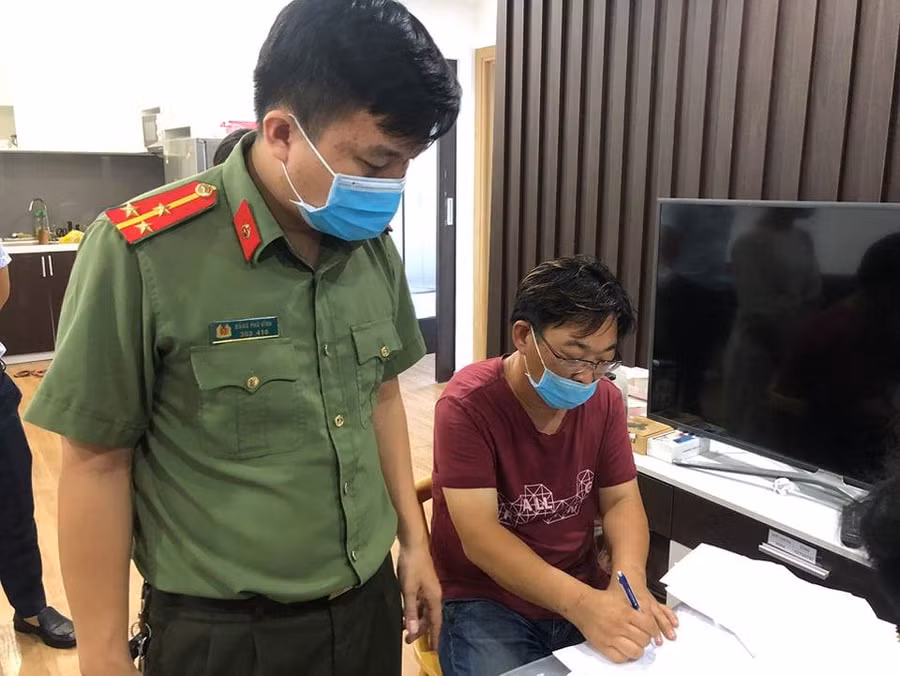 Bị can SONG HONG SUB (áo đỏ) đang ký vào lệnh bắt tạm giam. Ảnh: Công an.