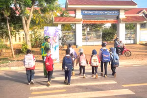 Học sinh tiểu học xã Đắk Song (Lâm Đồng) được hướng dẫn qua đường khi đến trường. (Ảnh: TT)