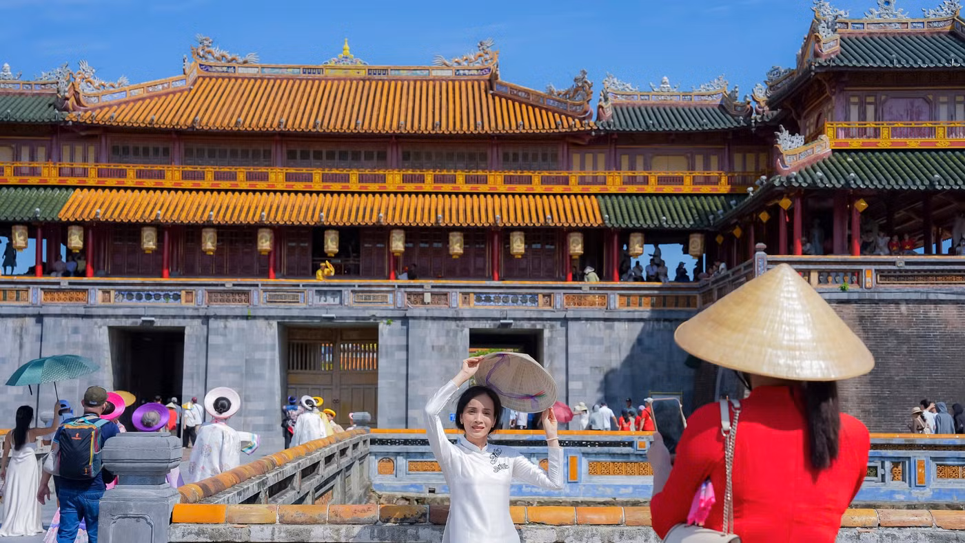 Người dân, du khách mặc áo dài, đội nón lá Huế chụp hình trước Đại Nội ngày lễ Quốc khánh 2026. (Ảnh: Đình Hoàng)