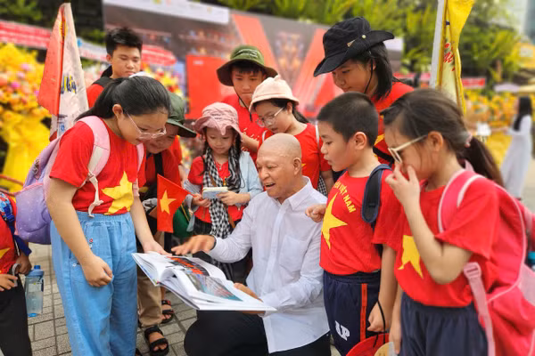 Nhiếp ảnh gia Nguyễn Á trò chuyện cùng các em học sinh tham quan triển lãm. Ảnh: L.N.