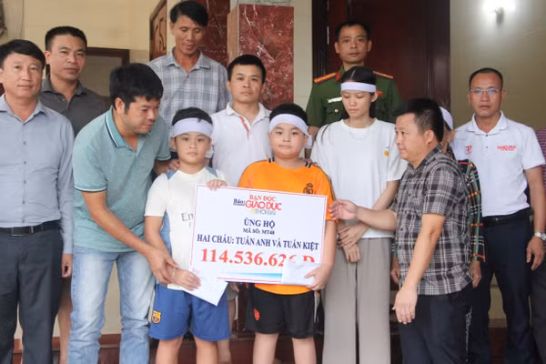 Đại diện Báo GD&TĐ cùng chính quyền địa phương trao quà bạn đọc đến 2 cháu nhỏ.