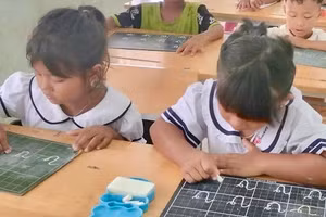 Học sinh người Cơ Ho nắn nót những nét chữ đầu tiên.