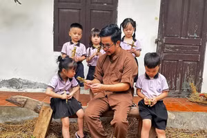 Nghệ nhân Nguyễn Tấn Phát hướng dẫn các em nhỏ làm hình nộm từ rơm.