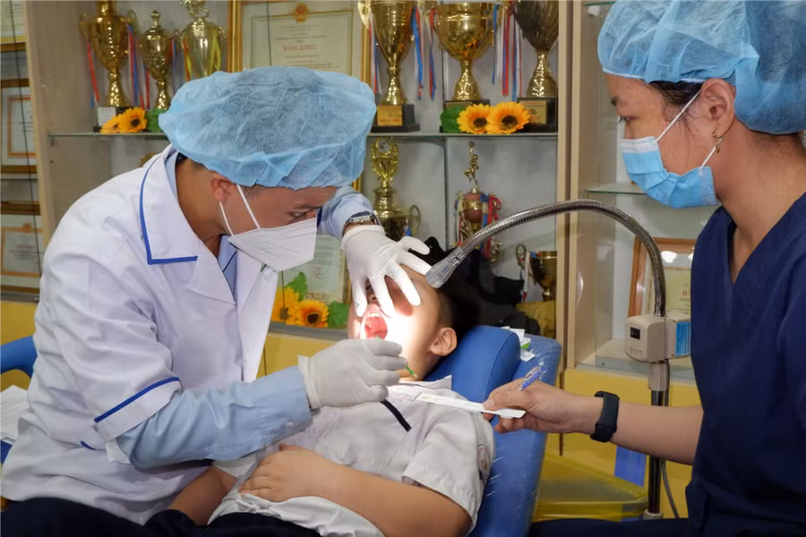 Bác sĩ Trung tâm y tế Quận 5 thực hiện khám răng cho học sinh dưới sự giám sát của các bác sĩ của Bệnh viện Răng Hàm Mặt Trung ương TPHCM. (Ảnh: SYT)