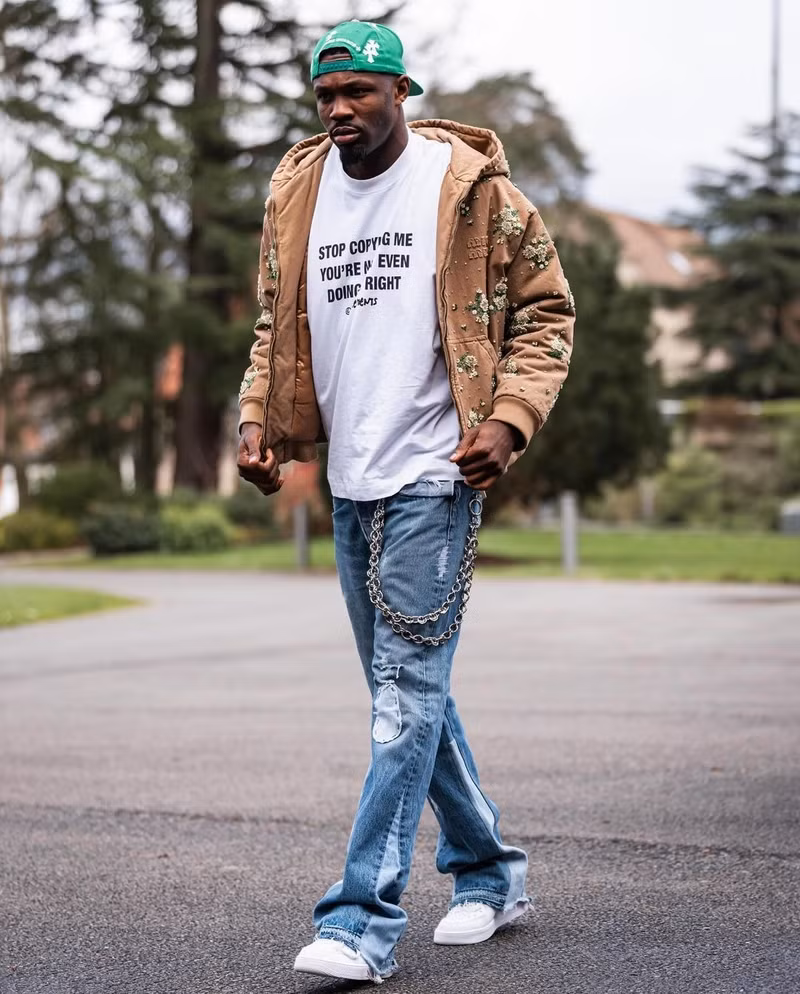 Tiền đạo Marcus Thuram phối áo thun trắng với quần jeans cách điệu và khoác áo đính hoa hiệu Miu Miu. Choáng với phong cách thời trang sành điệu của dàn sao tuyển Pháp