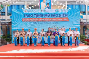Các đại biểu trao tặng mũ bảo hiểm cho các em học sinh lớp Một trường Tiểu học Ngô Mây.