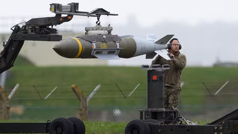 Đội kỹ thuật mặt đất di chuyển các quả bom dẫn đường chính xác JDAM trước khi chúng được nạp vào máy bay ném bom hạng nặng Rockwell B1 Lancer tại căn cứ RAF Fairford ngày 16/3 ở Anh. 