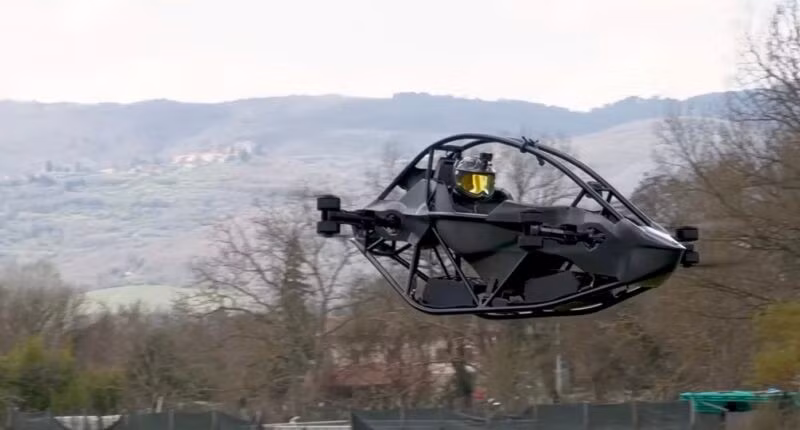 Máy bay eVTOL Jetson ONE đang bay giữa không trung trên một cánh đồng với dãy núi phía sau. Ảnh: Jetson