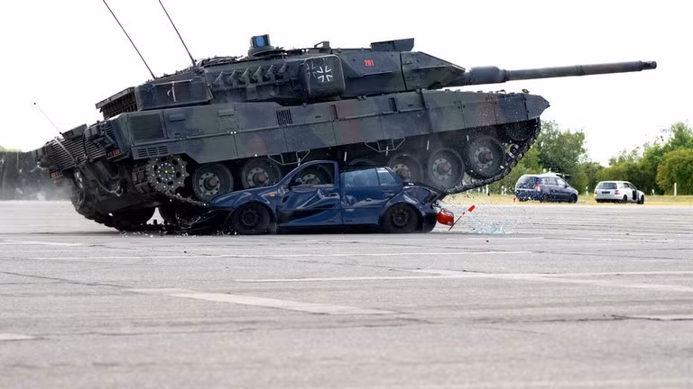 Các binh sĩ Đức trình diễn khả năng của xe tăng chiến đấu chủ lực Leopard 2A7V và lái xe cán qua một chiếc VW Golf cũ trong Ngày Quân đội trên khuôn viên Đại học Bundeswehr. 