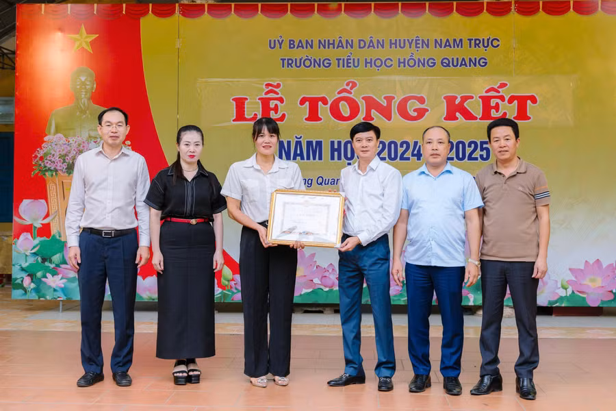 Giám đốc Sở GD&ĐT Nam Định Nguyễn Xuân Hồng trao Giấy khen cho hành động dũng cảm cứu người của cô Nguyễn Thị Mai. Ảnh: Nhà trường cung cấp. 