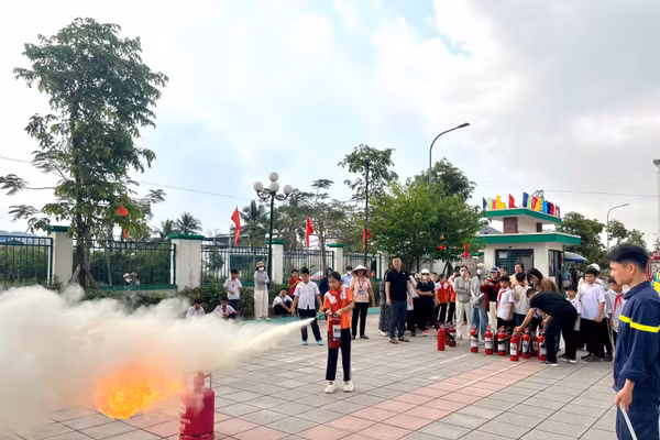 Các em học sinh thực hành sử dụng bình chữa cháy dập tắt đám cháy giả định.