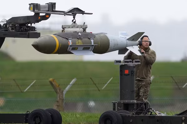 Đội kỹ thuật mặt đất di chuyển các quả bom dẫn đường chính xác JDAM trước khi chúng được nạp vào máy bay ném bom hạng nặng Rockwell B1 Lancer tại căn cứ RAF Fairford ngày 16/3 ở Anh. 